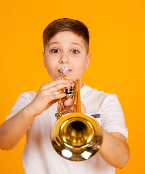 Zu sehen ist ein Junge, der Trompete spielt.