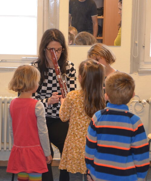 Zu sehen ist eine Oboe Lehrerin, die Kindern ihre Oboe erklärt.