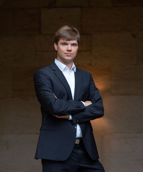 Zu sehen ist Musiker Alexander Sonderegger in einem historischen Portal aus grauen Mauersteinen