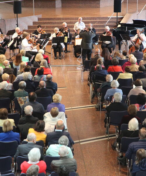 Zu sehen sind Zuschauer die einem Orchester zuhören.