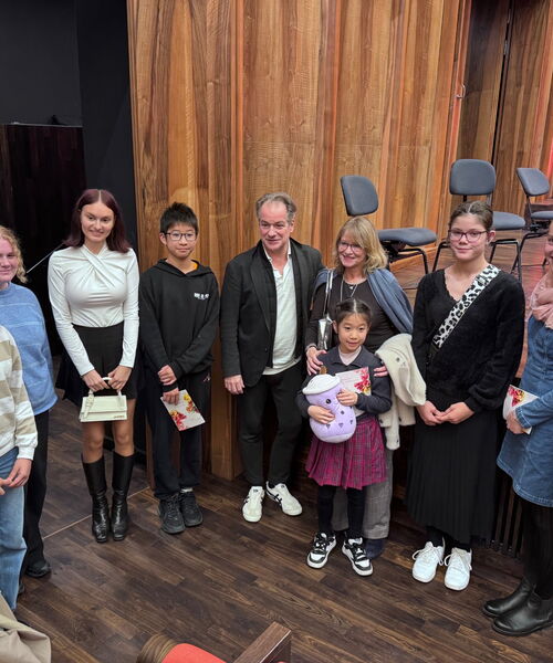 Zu sehen sind die Schülerinnen und Schüler der Exkursion vor einer Bühne stehend