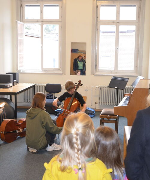 Zu sehen sind Kinder und Jugendliche die Musikintrumente ausprobieren